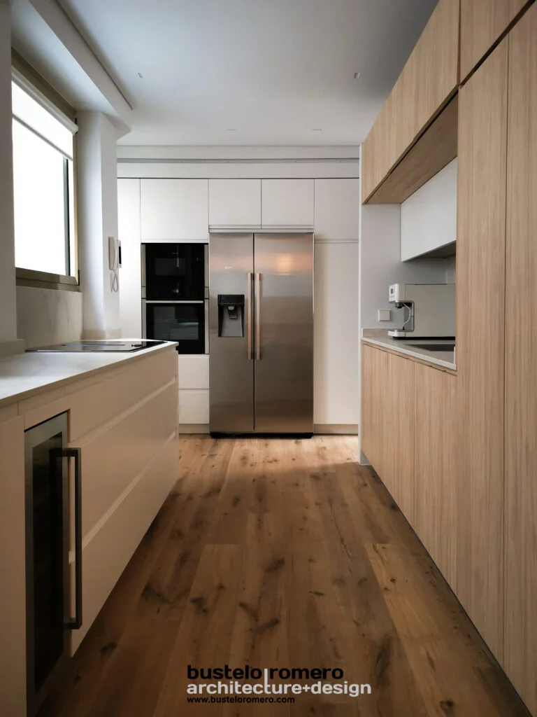 Cocina alargada de estilo minimalista con maderas nobles y luz natural, diseñada por estudio de arquitectura en Toledo.